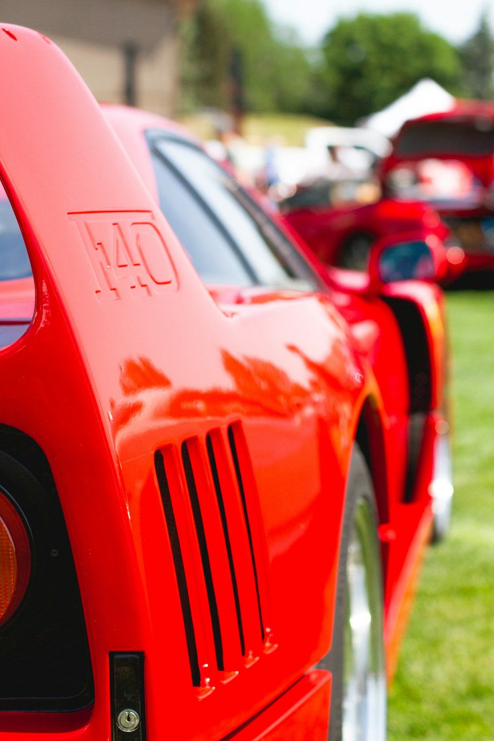 Coche rojo aparcado en un campo de hierba verde durante el día