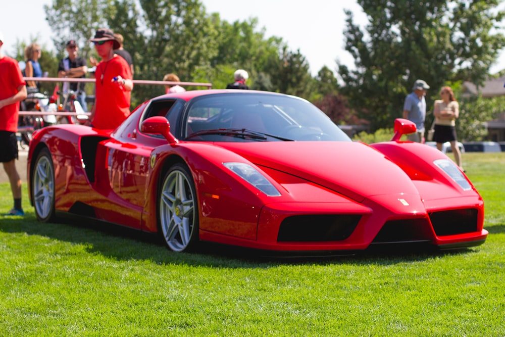 red ferrari 458 italia on green grass field during daytime