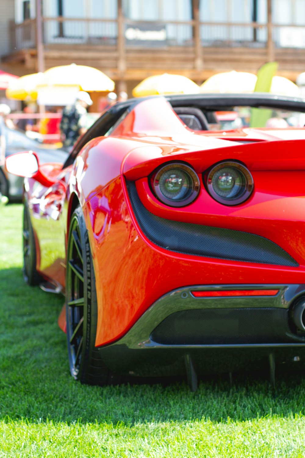 red ferrari car on green grass field during daytime