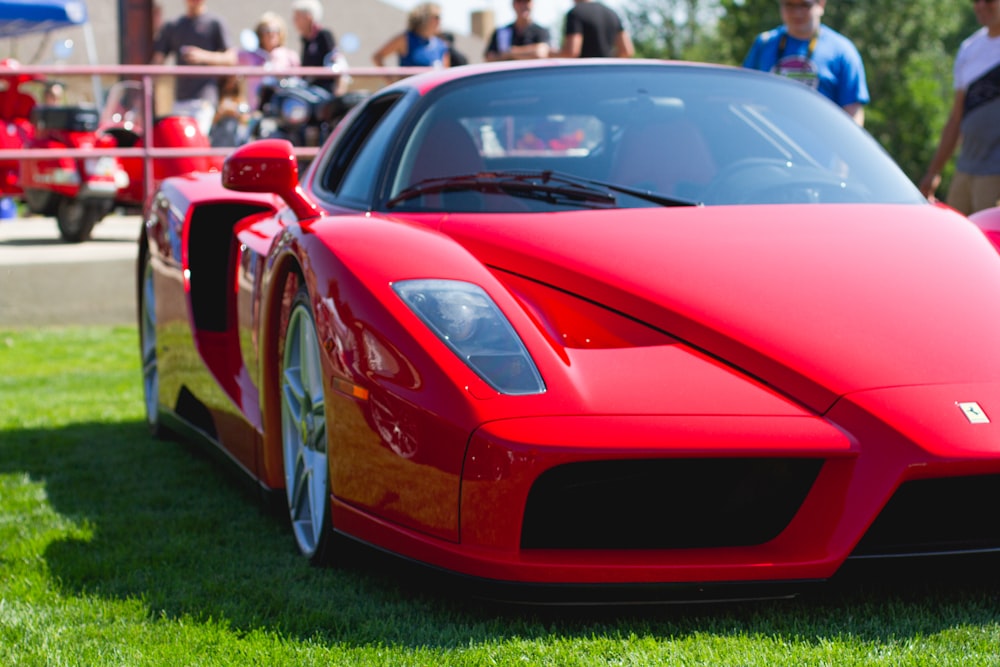 red ferrari 458 italia on green grass field during daytime