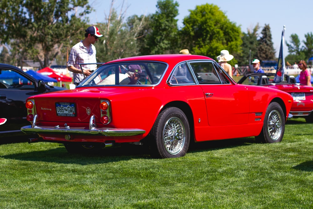 red porsche 911 parked on green grass field during daytime