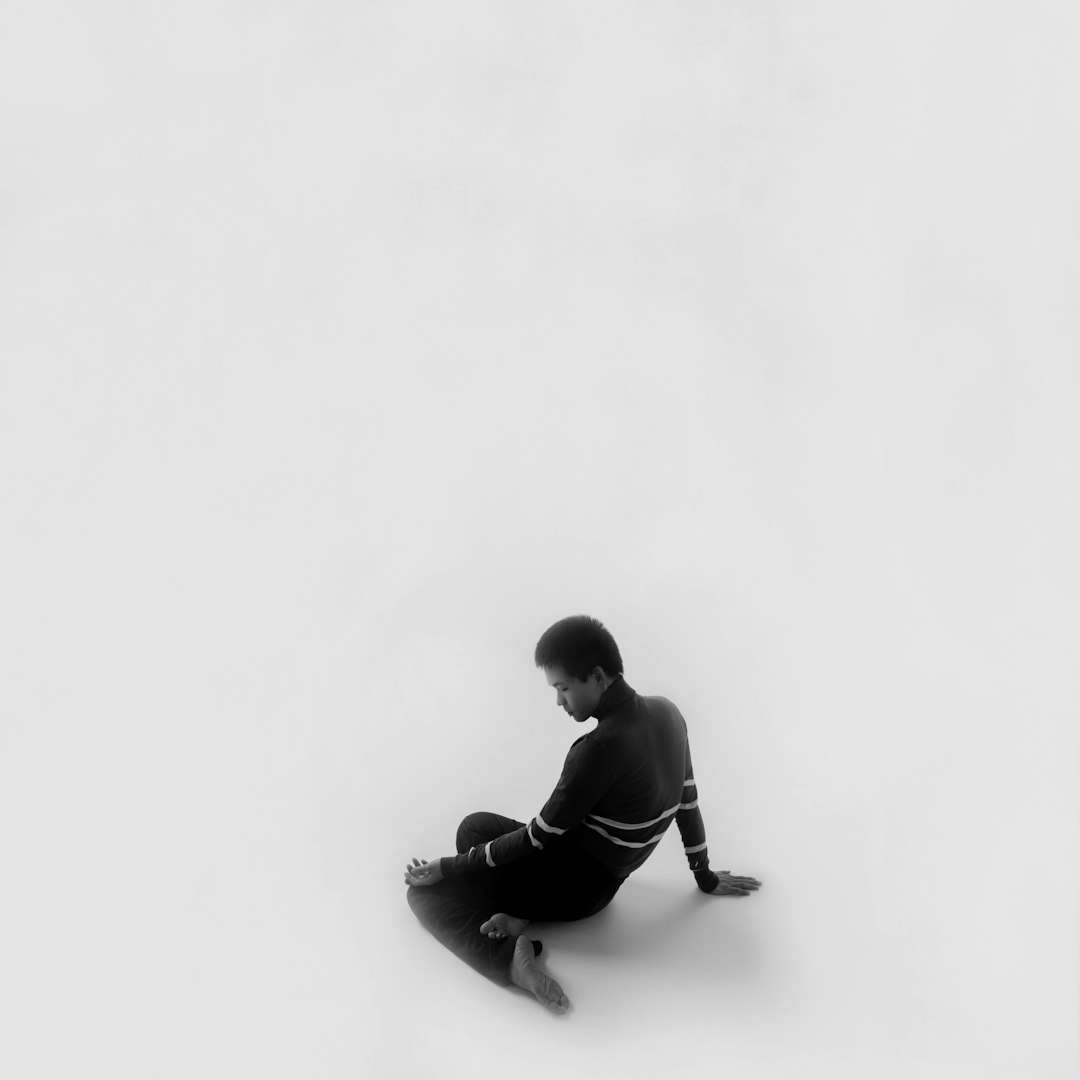 man in black hoodie sitting on white floor