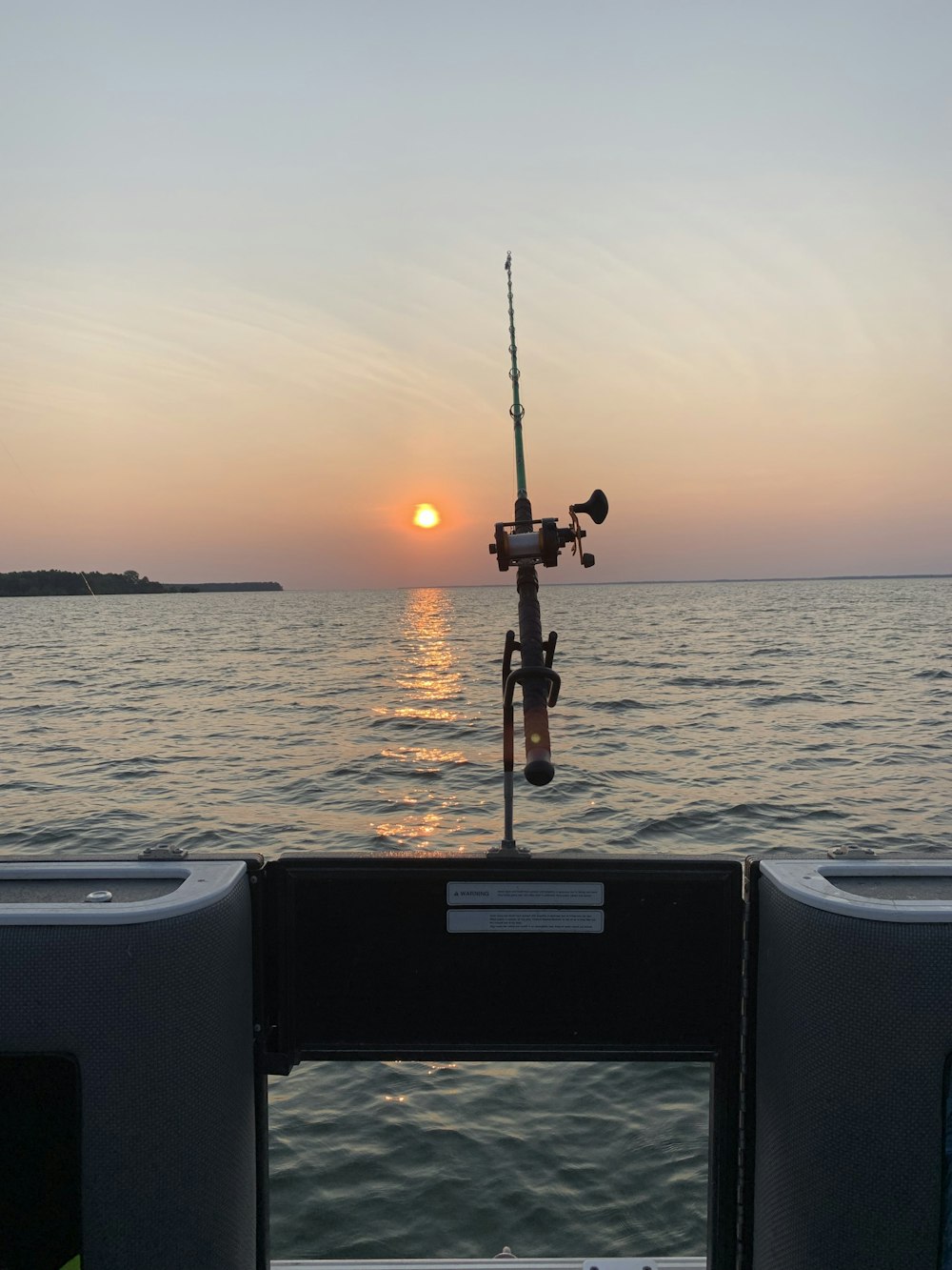 Caña de pescar negra en barco blanco durante la puesta del sol