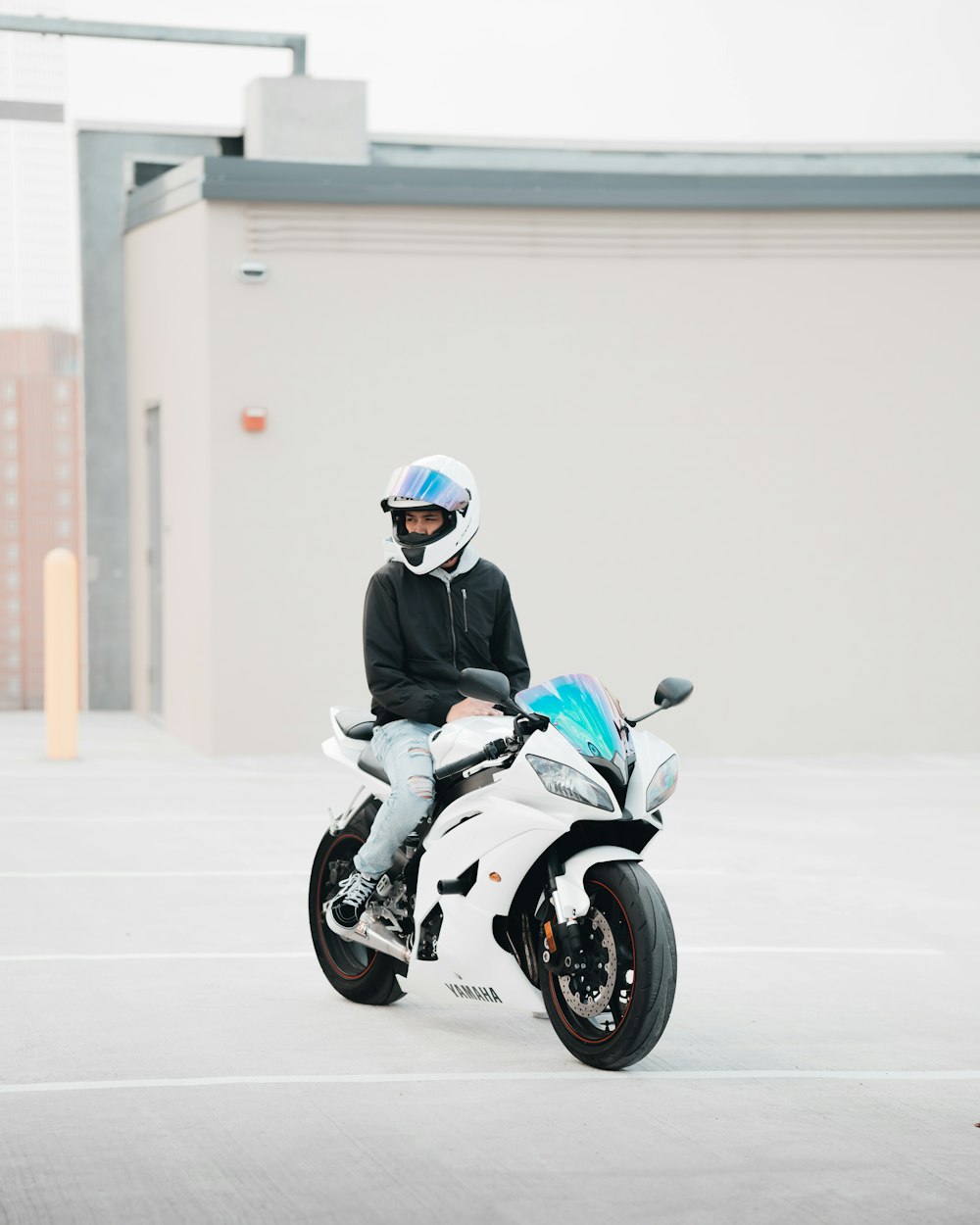 man in black jacket riding on black and white sports bike