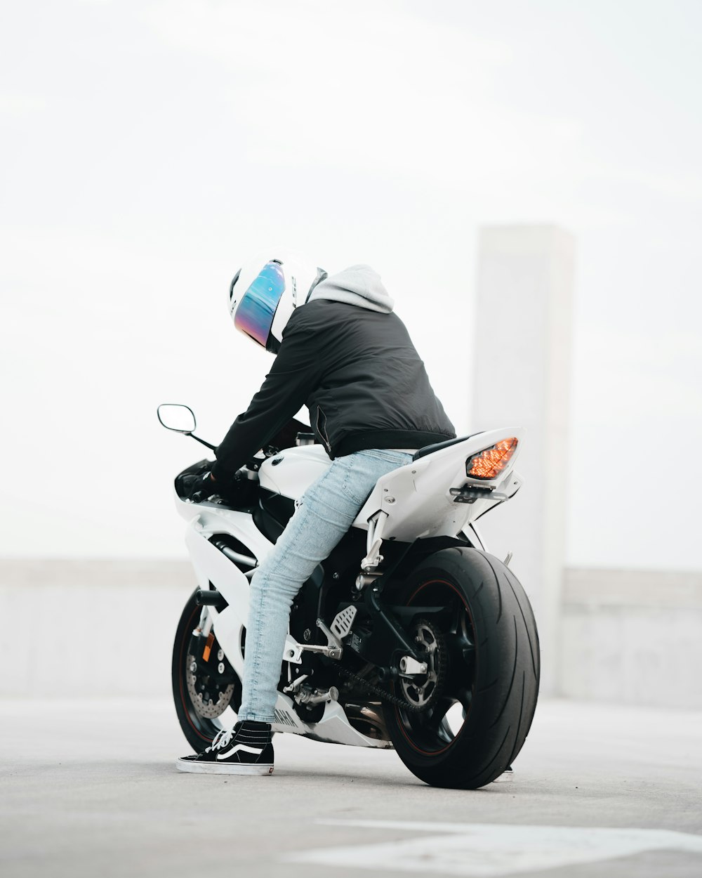 man in black jacket riding on white and black sports bike