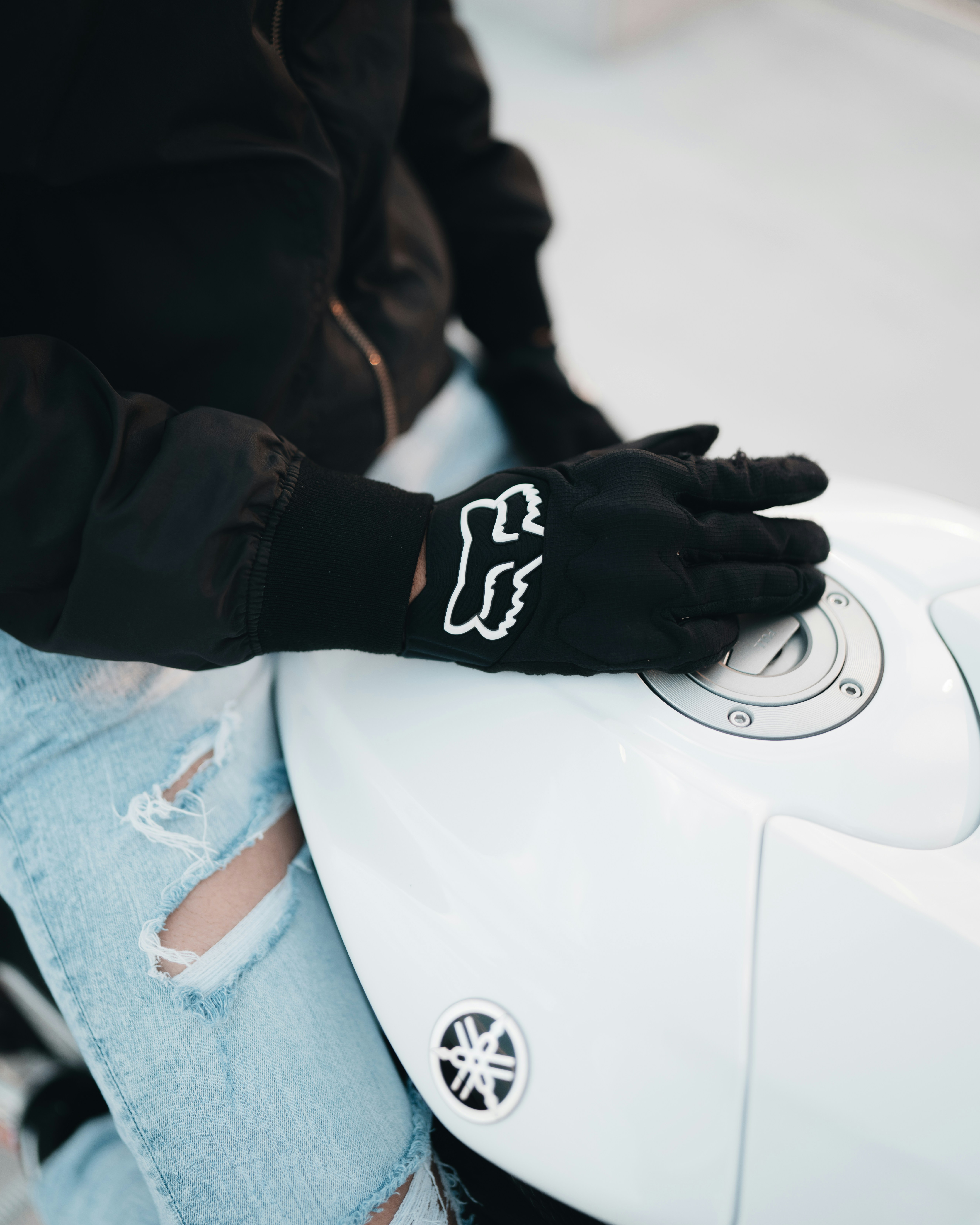 Persona in giacca nera e jeans blu in denim che si siede sulla sedia bianca