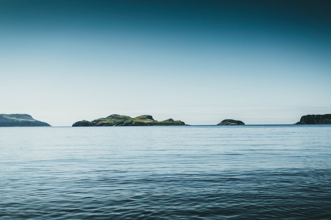 black rock formation on sea under blue sky during daytime