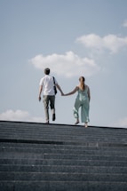 man in white t-shirt and woman in teal tank top on gray concrete stairs during