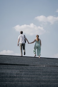 man in white t-shirt and woman in teal tank top on gray concrete stairs during