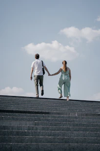 man in white t-shirt and woman in teal tank top on gray concrete stairs during