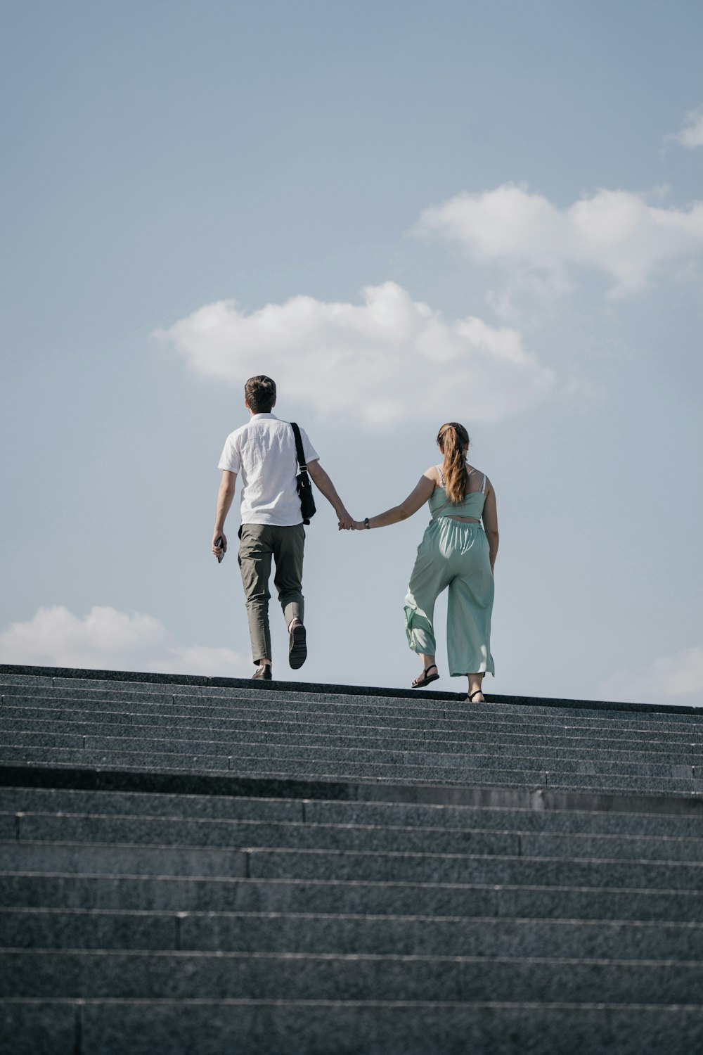 uomo in maglietta bianca e donna in canotta verde acqua su scale di cemento grigio durante