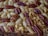 A close-up view of a baked dessert featuring a combination of pecans, walnuts, and almonds embedded in a golden-brown crust.