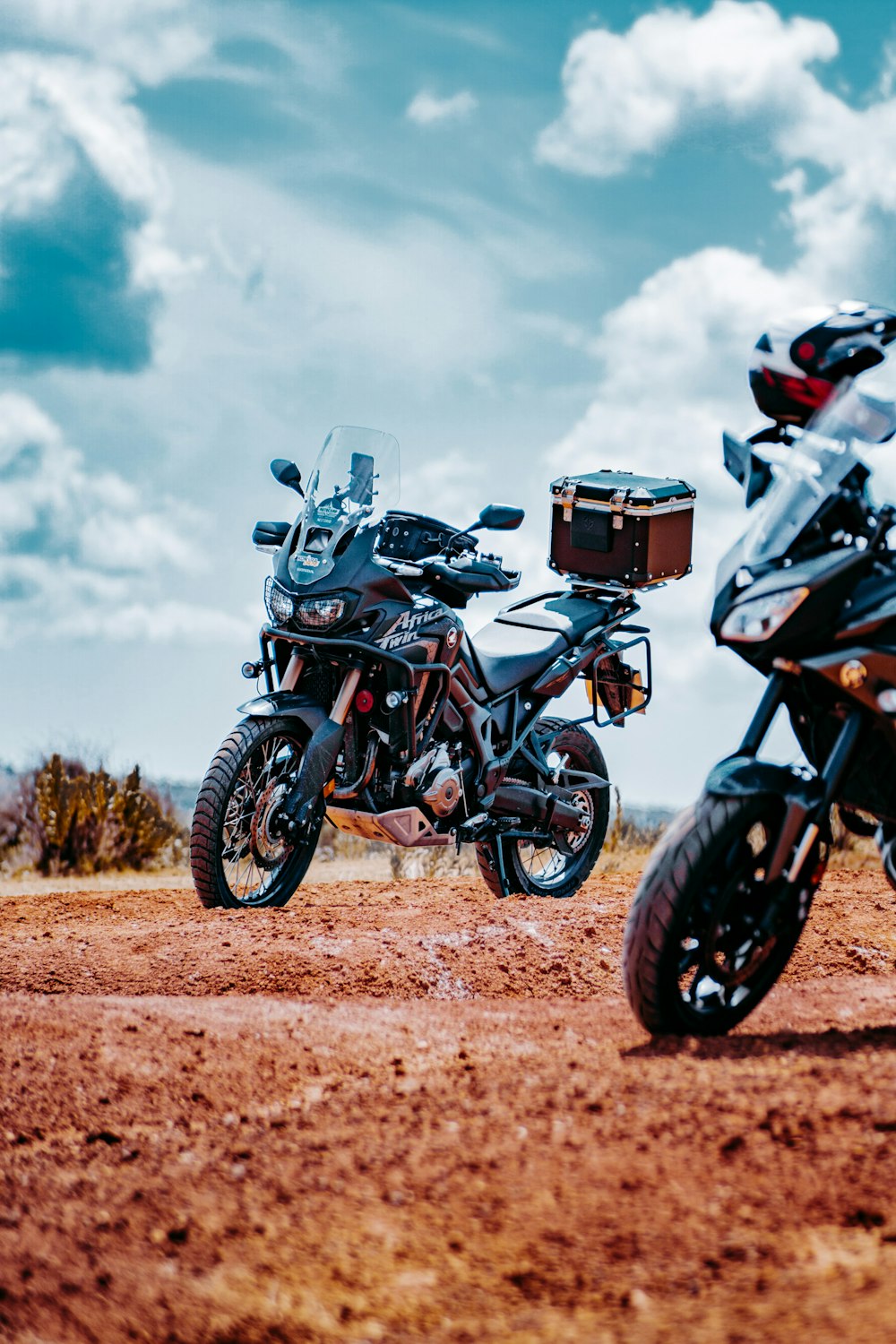 black and orange motorcycle on brown dirt road under white clouds during daytime