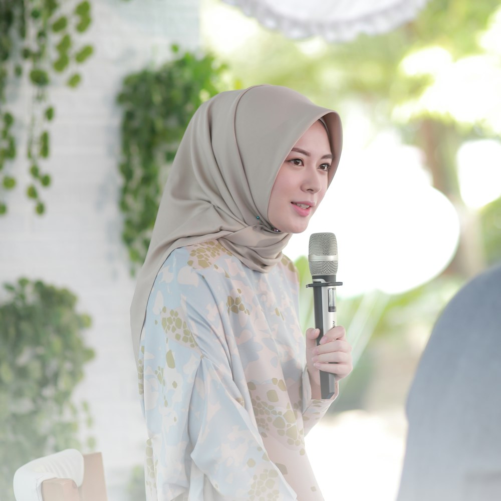 Frau in weißem und blauem geblümtem Hijab mit Mikrofon