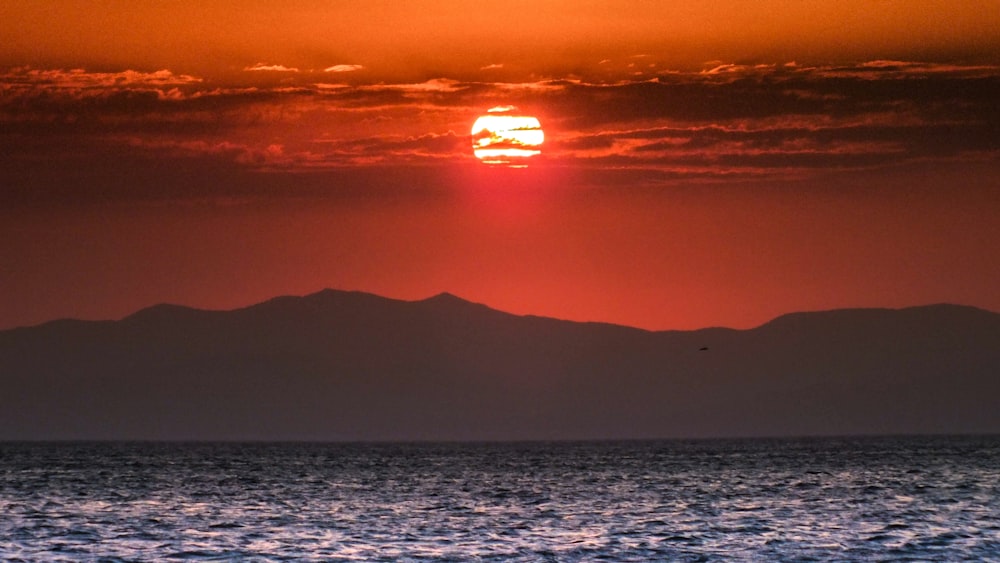 body of water near mountain during sunset