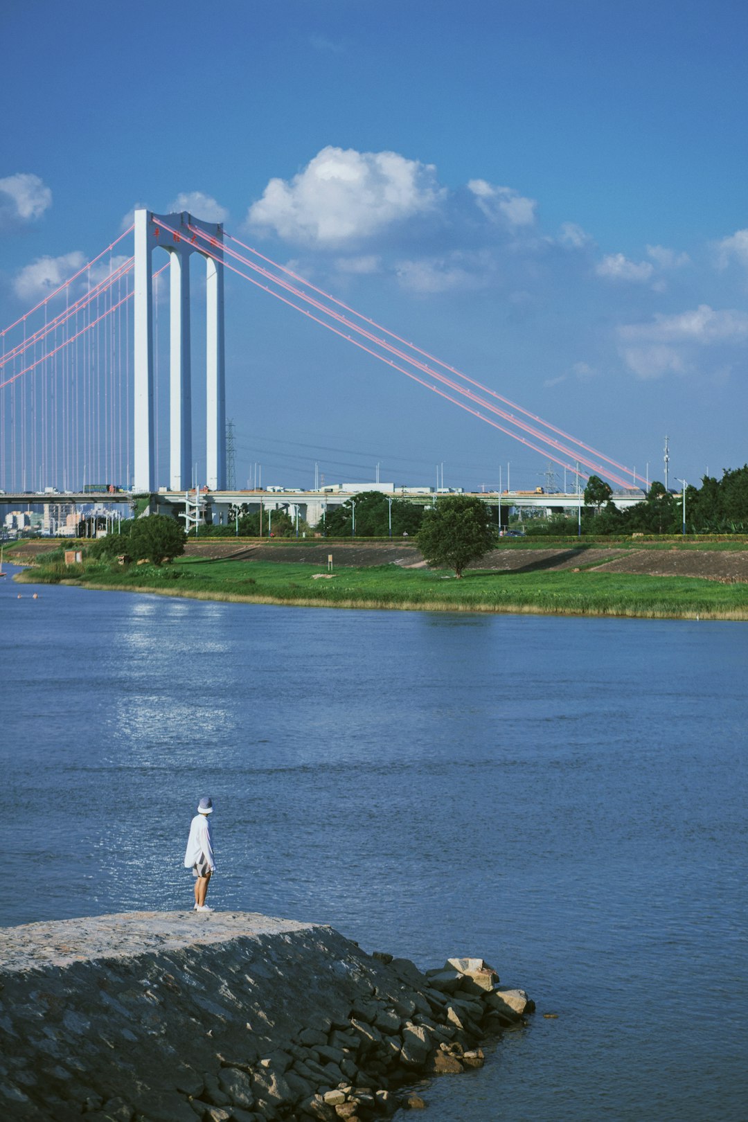 woman in white dress standing on green grass field near bridge during daytime