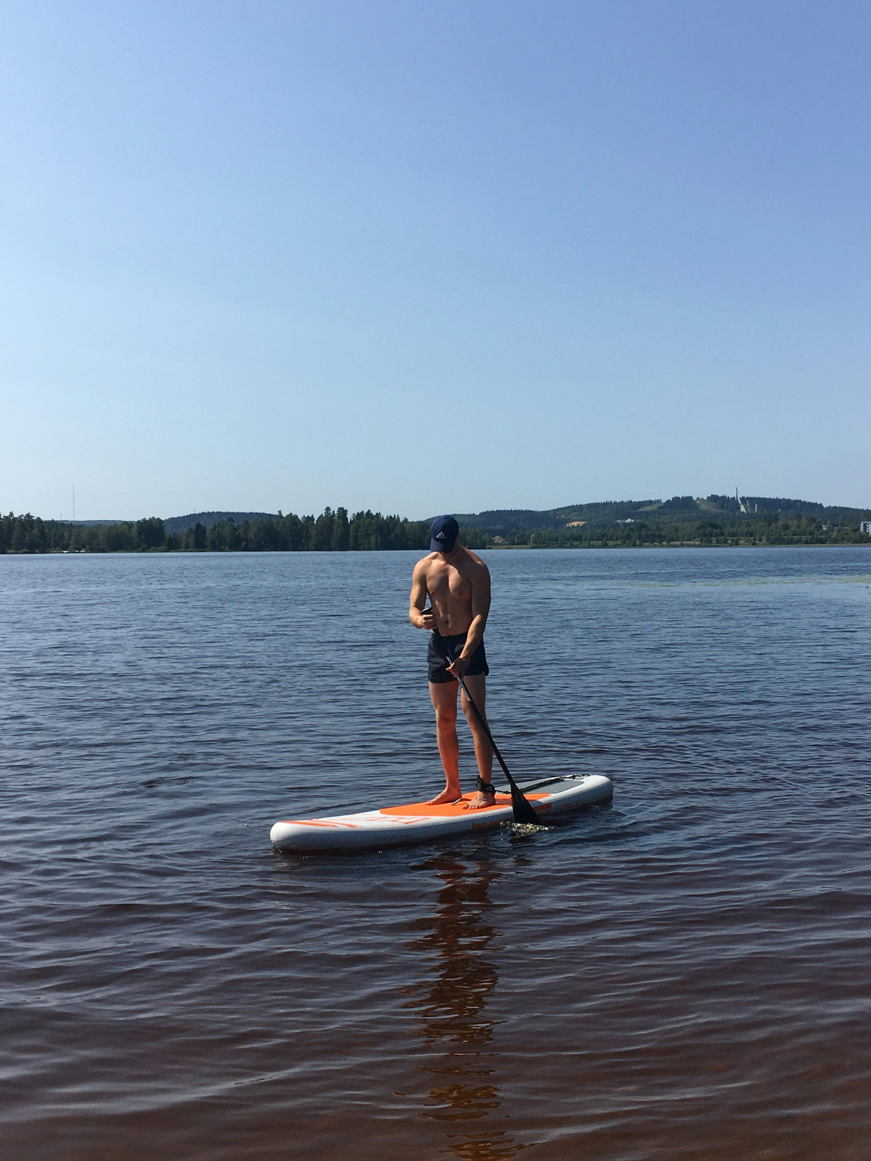 woman in black bikini riding orange kayak on sea during daytime