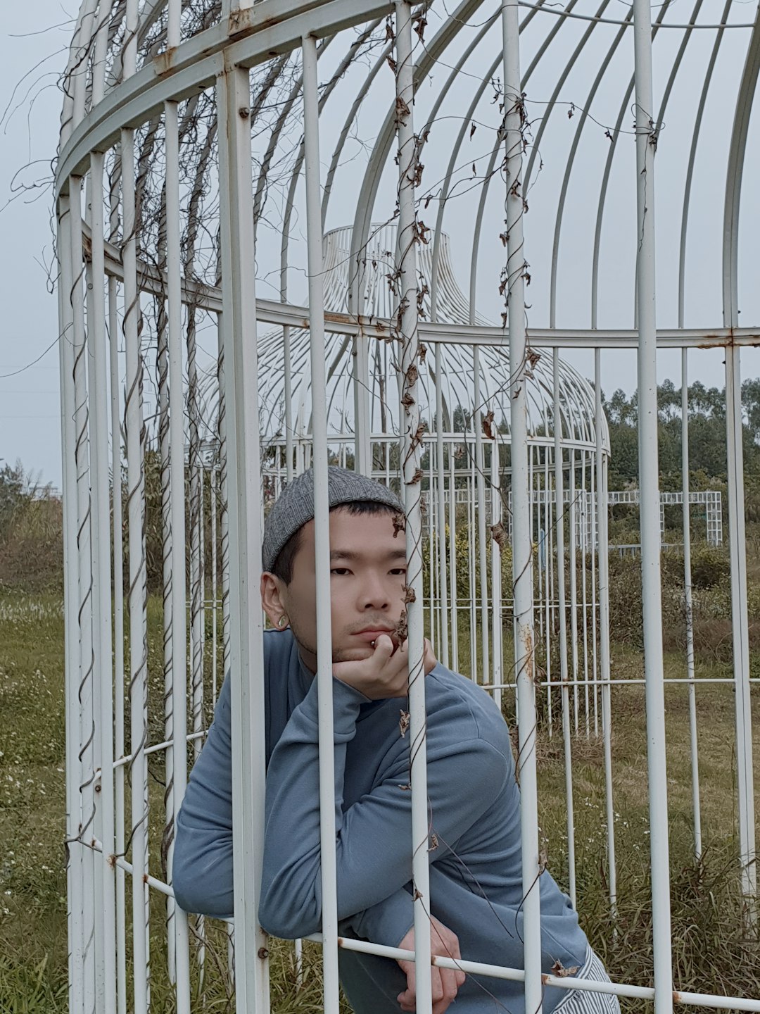 man in blue jacket standing near white metal fence during daytime