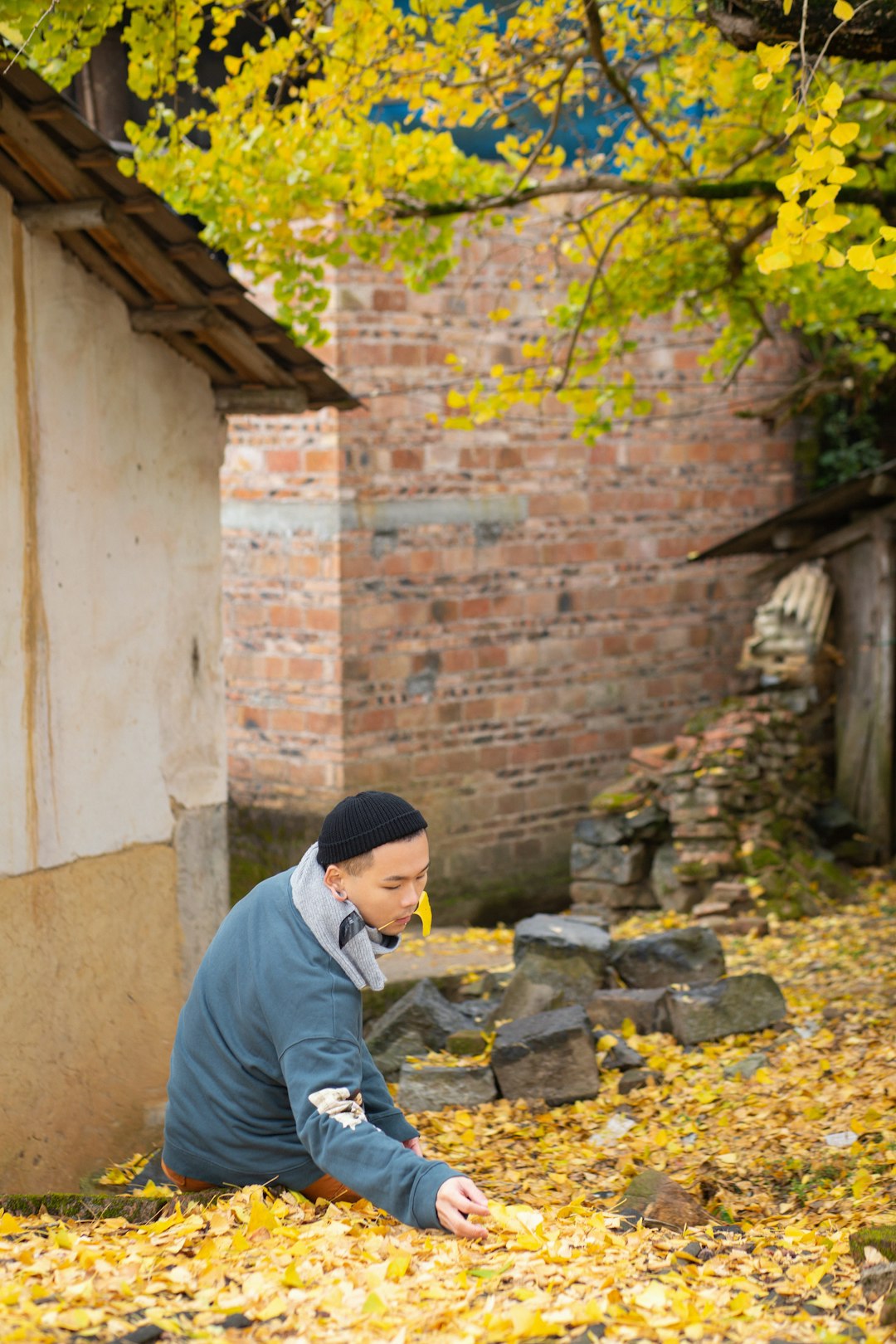 man in gray long sleeve shirt and black knit cap sitting on gray concrete bricks during