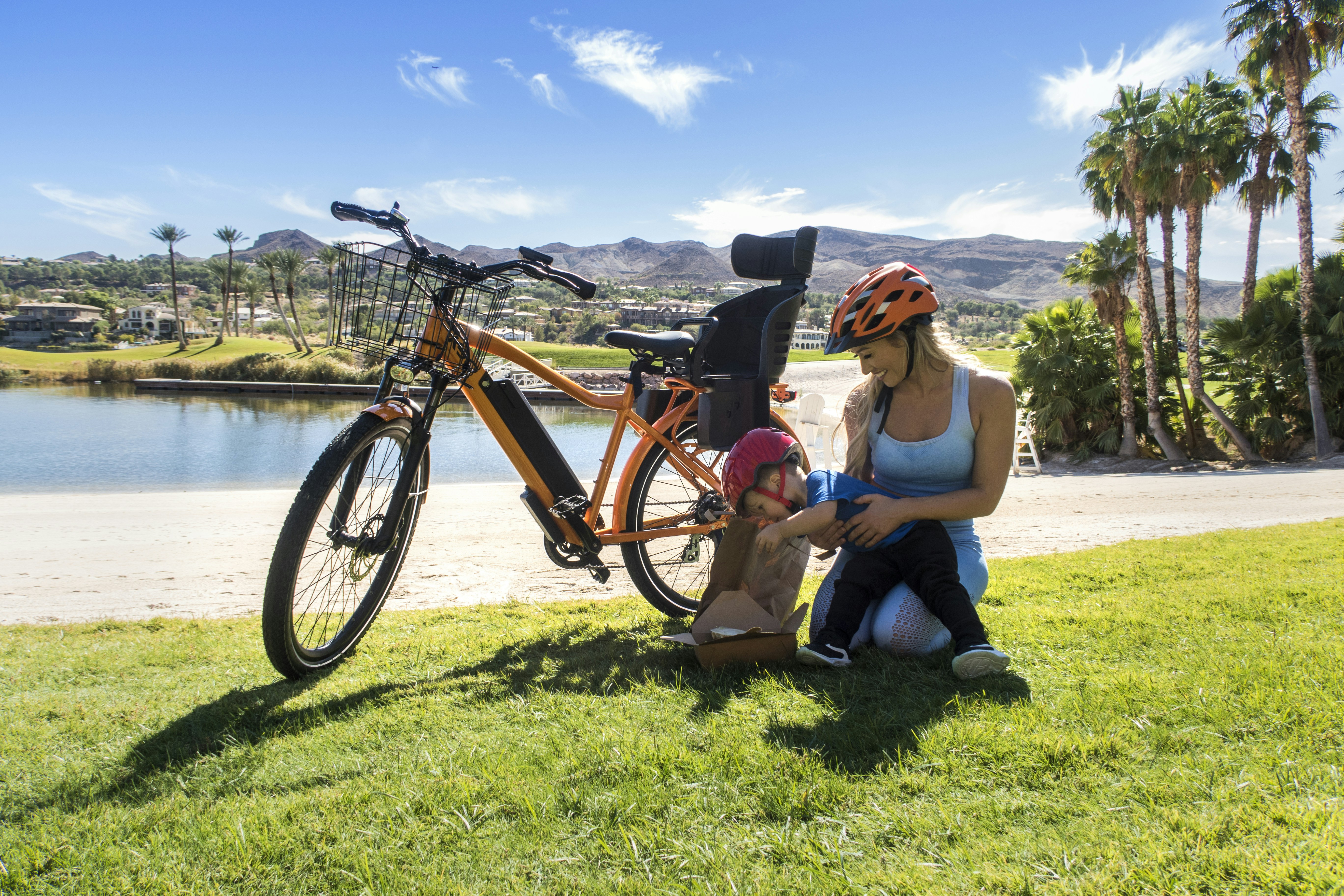 woman in blue tank top and blue denim shorts sitting on green grass field beside orange