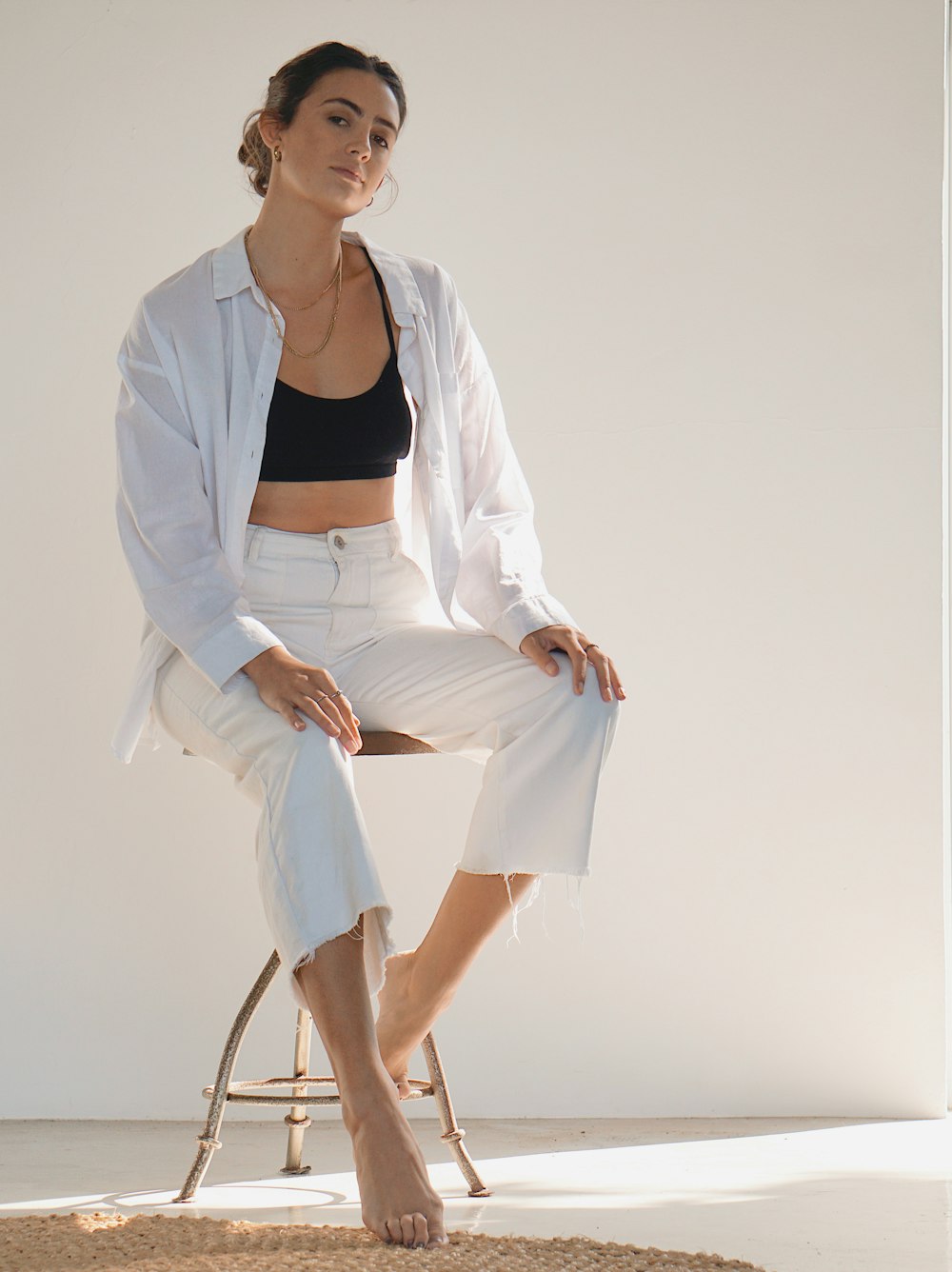 donna in blazer bianco e camicia bianca seduta sulla sedia