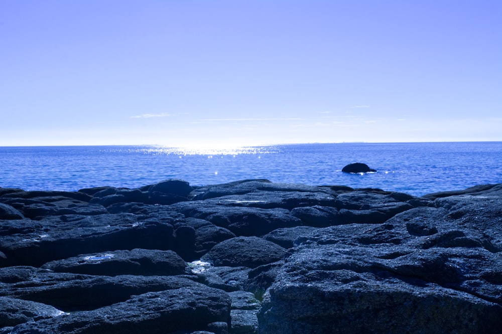 black rock formation on sea under blue sky during daytime