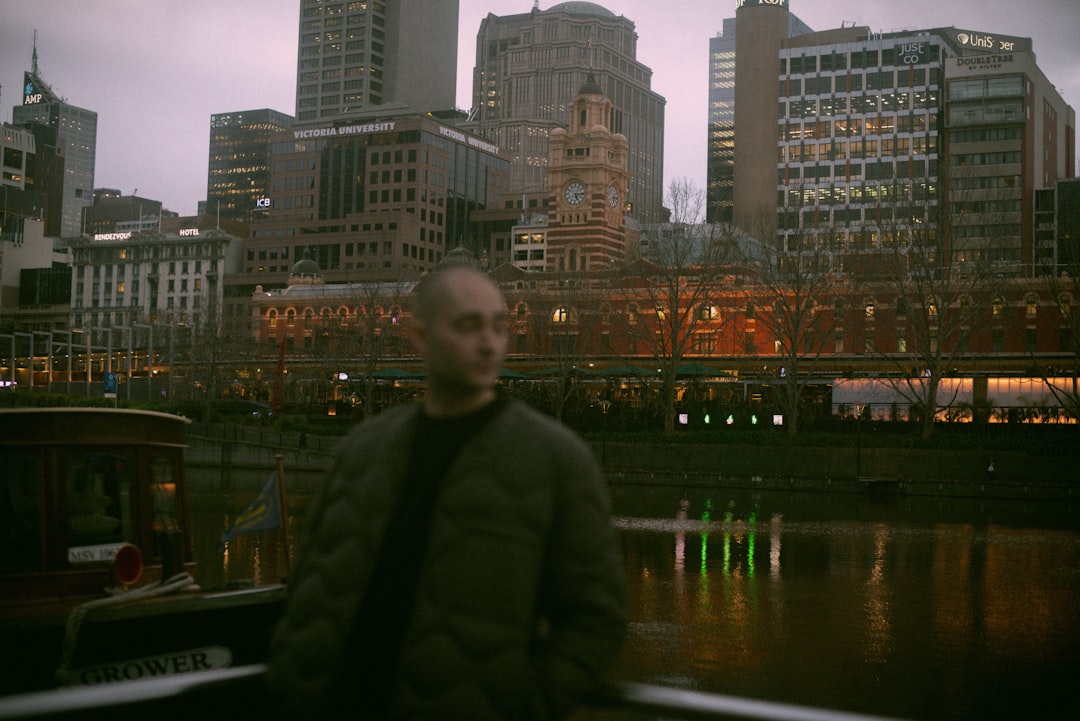 man in green jacket standing near body of water during night time