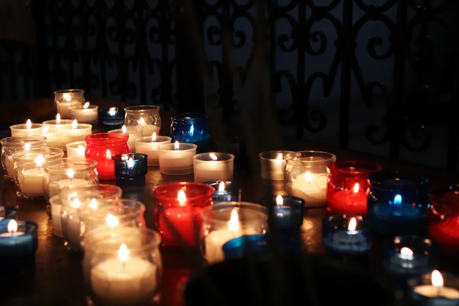 Rows of lit prayer candles in red and white glass holders