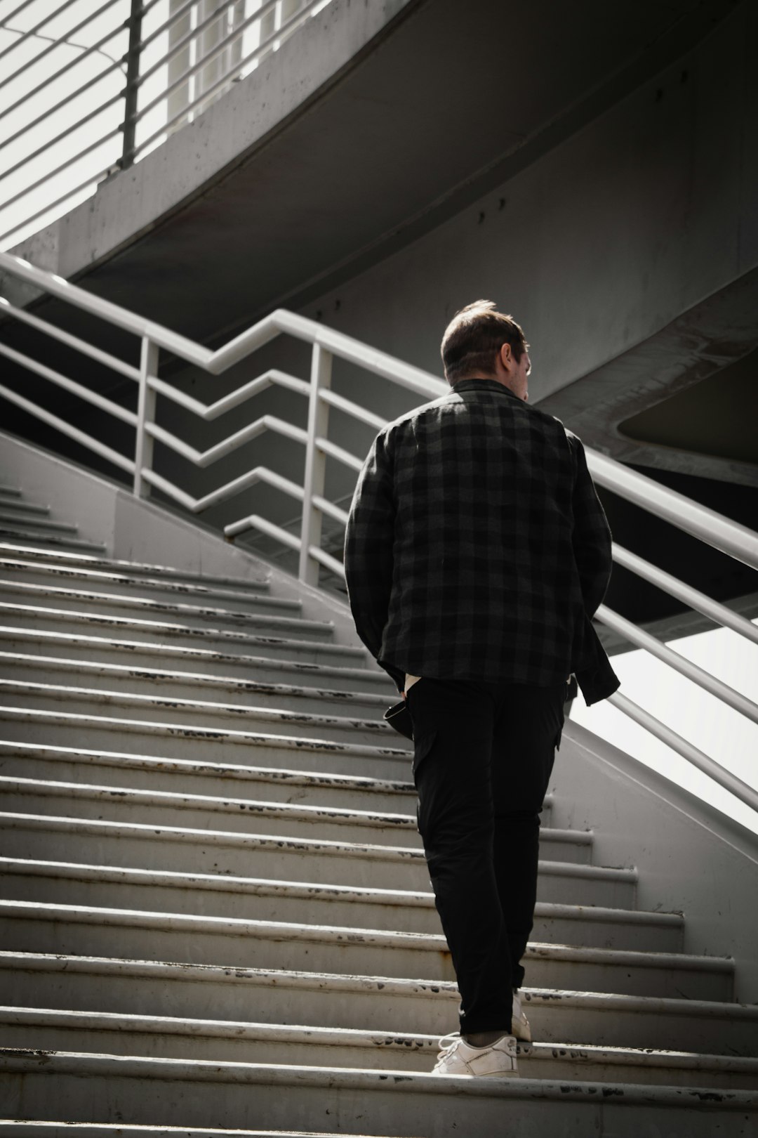 man in black and white checkered dress shirt and black pants standing on white staircase