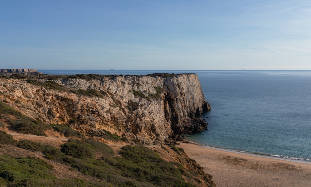 brown and green mountain beside blue sea under blue sky during daytime