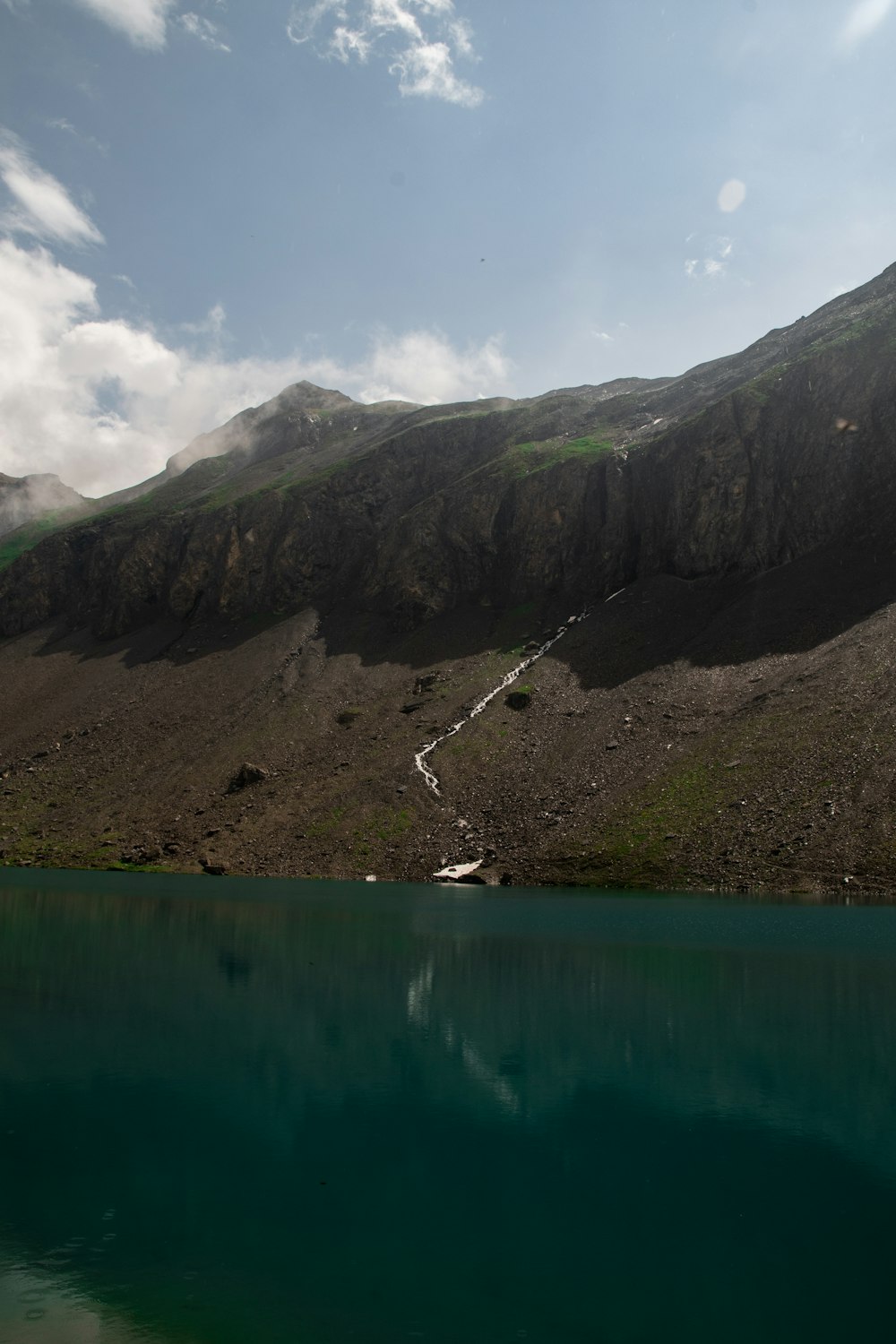 lake near mountain under blue sky during daytime