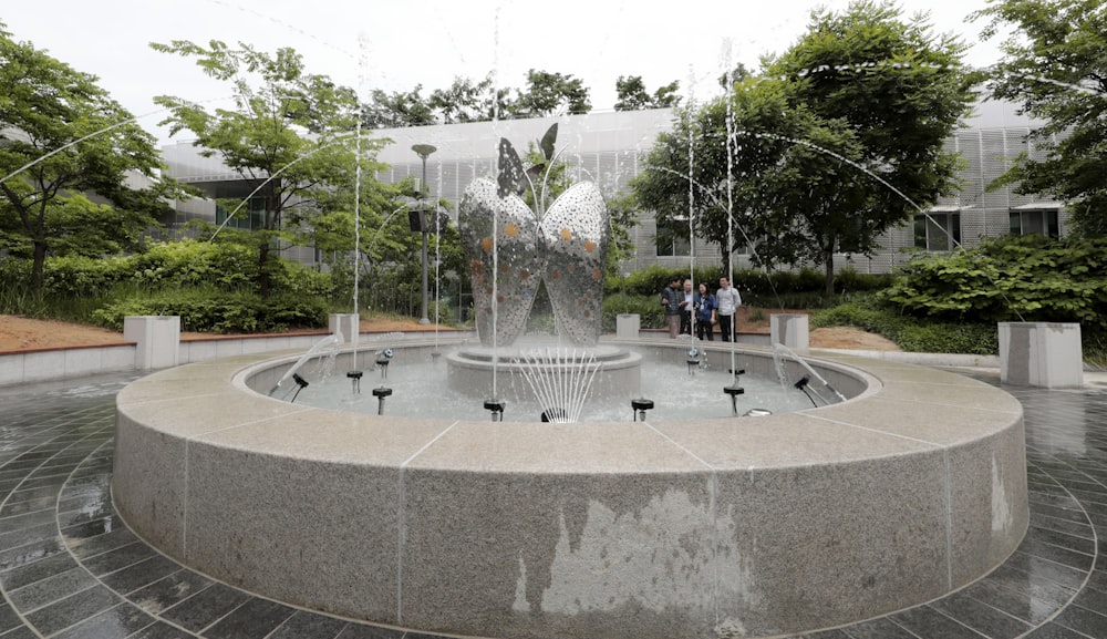 people sitting on outdoor fountain during daytime