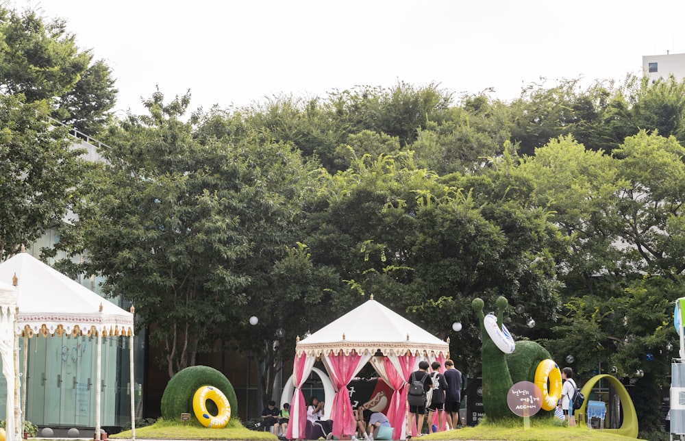 people sitting on red and white tent near green trees during daytime