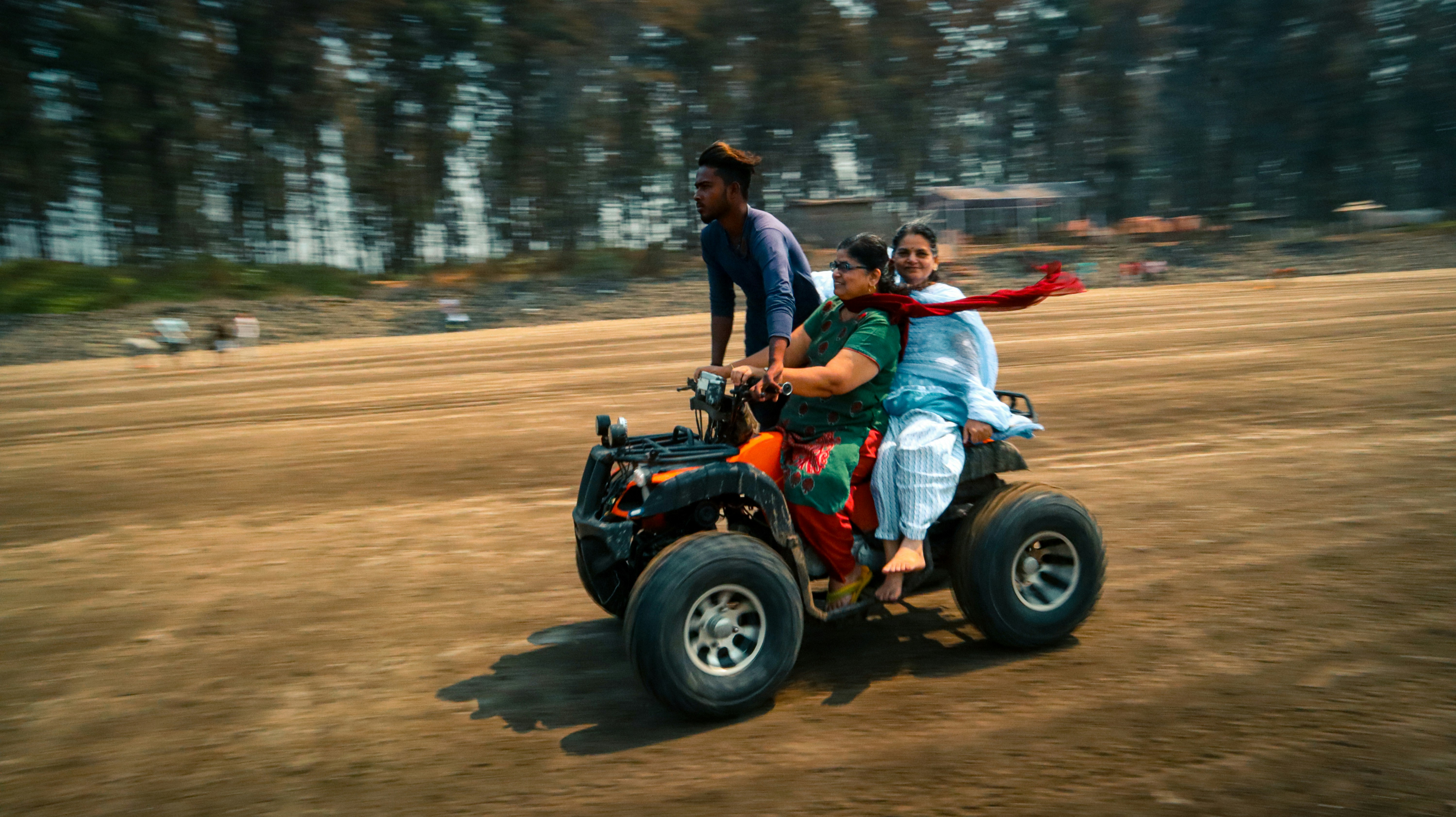 2 men riding on red atv on road during daytime