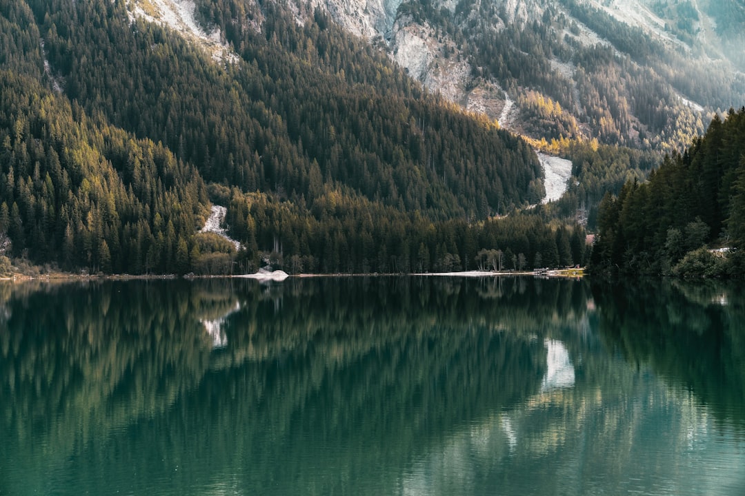 green and white mountains beside lake during daytime