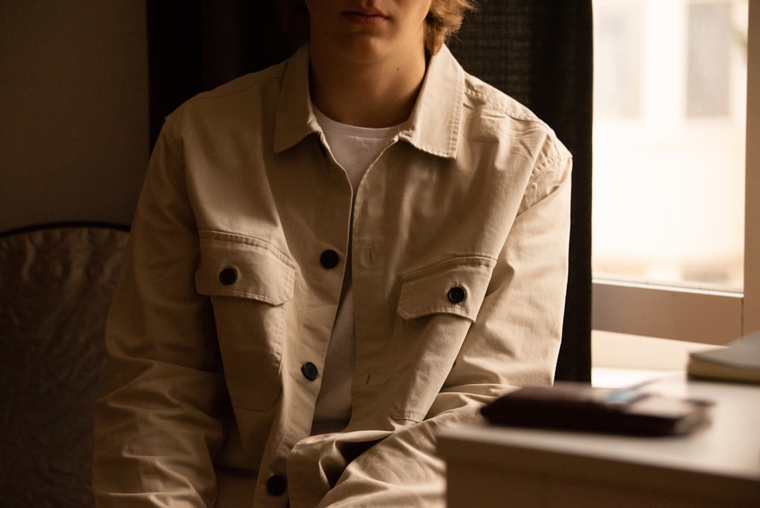 man in gray button up shirt sitting beside window
