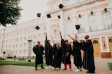 people in black academic dress standing on green grass field during daytime