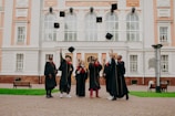 people in black academic dress standing on brown concrete floor during daytime