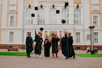 people in black academic dress standing on brown concrete floor during daytime