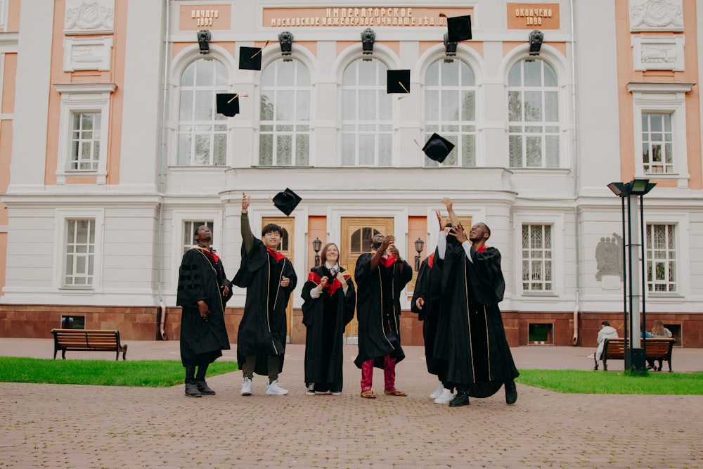 people in black academic dress standing on brown concrete floor during daytime