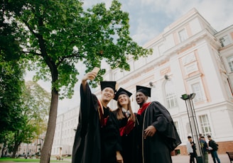 3 women in black academic dress standing near green tree during daytime