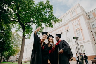 3 women in black academic dress standing near green tree during daytime