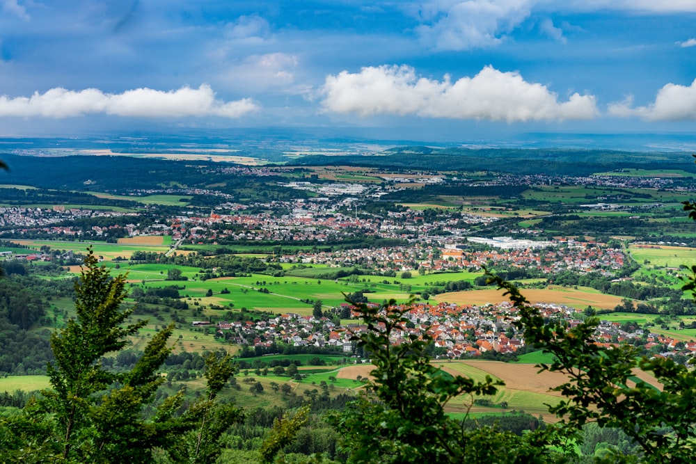 aerial view of green trees and buildings under blue sky and white clouds during daytime