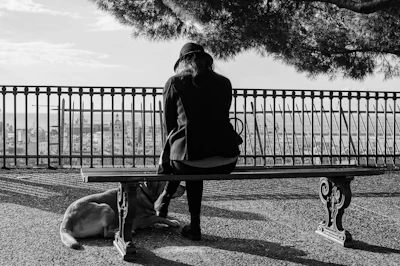 A resident meditating on a bench with a dog resting its head on their lap.