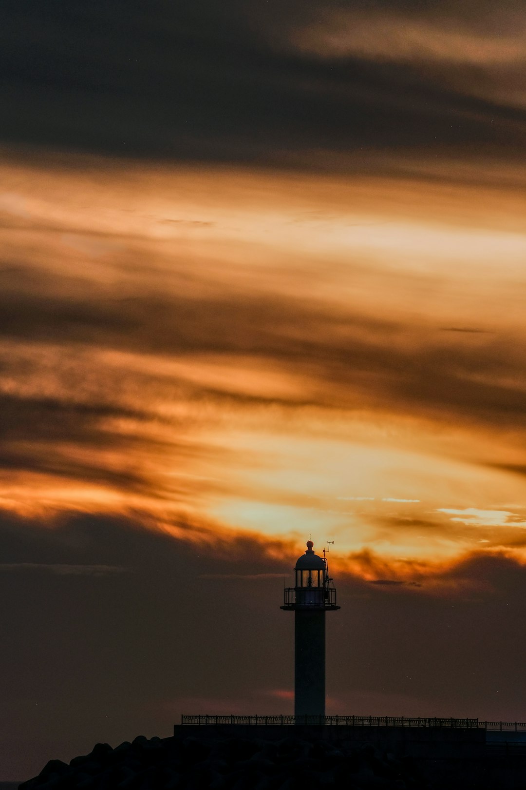 white and black lighthouse under cloudy sky during sunset