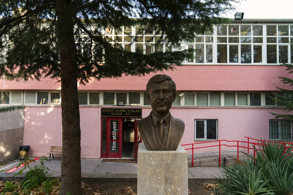 brown concrete statue near red building during daytime