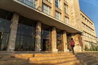 A cheerful student with backpack entering a modern school building.