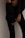 A person wearing dark clothing is standing against a plain wall. The outfit consists of fitted pants and a loosely buttoned shirt, partially revealing an undergarment. The focus is on the lower torso and legs.