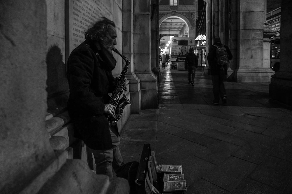 man playing saxophone in grayscale photography