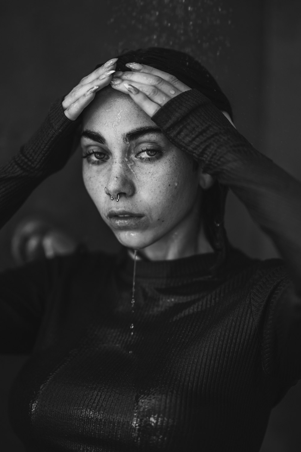 a black and white photo of a woman with her hands on her head